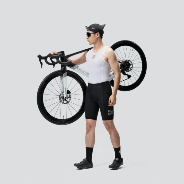 Ciclista con culotte de ciclismo Rockbros negro cargando una bicicleta de ruta al hombro