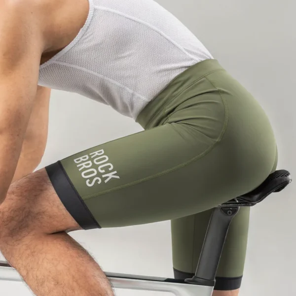 Ciclista pedaleando con culotte Rockbros verde oliva, vista lateral del muslo con logo ROCK BROS y ribete negro