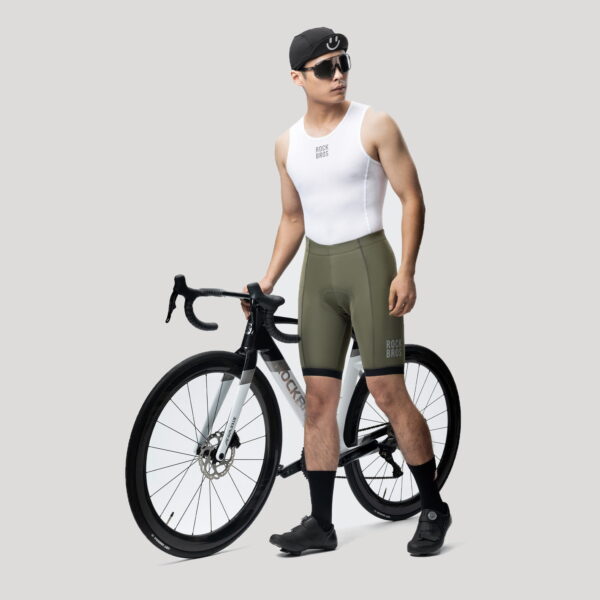 Ciclista con culotte Rockbros verde oliva junto a una bicicleta de pista