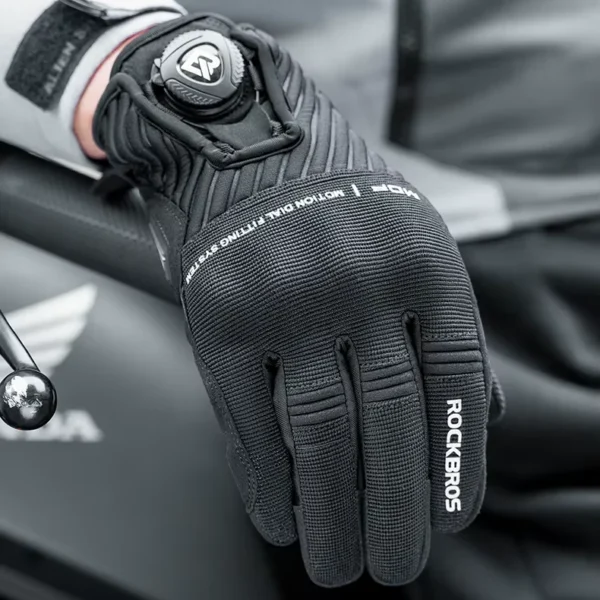 Guante Rockbros GMT5300 negro sobre el tanque de la moto, con la perilla de ajuste en la muñeca