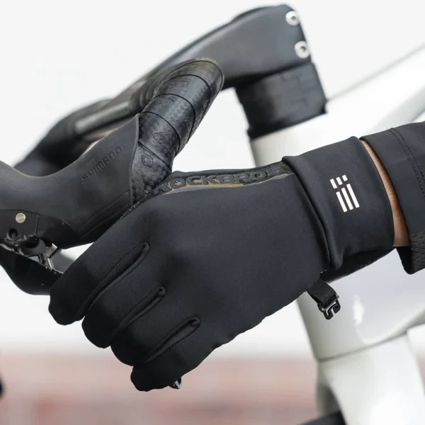 Guantes térmicos Rockbros S6600 negros sobre el manillar de una bici de ruta